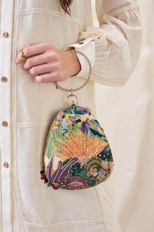 Colorful embroidered clutch held by a person wearing a beige jacket.