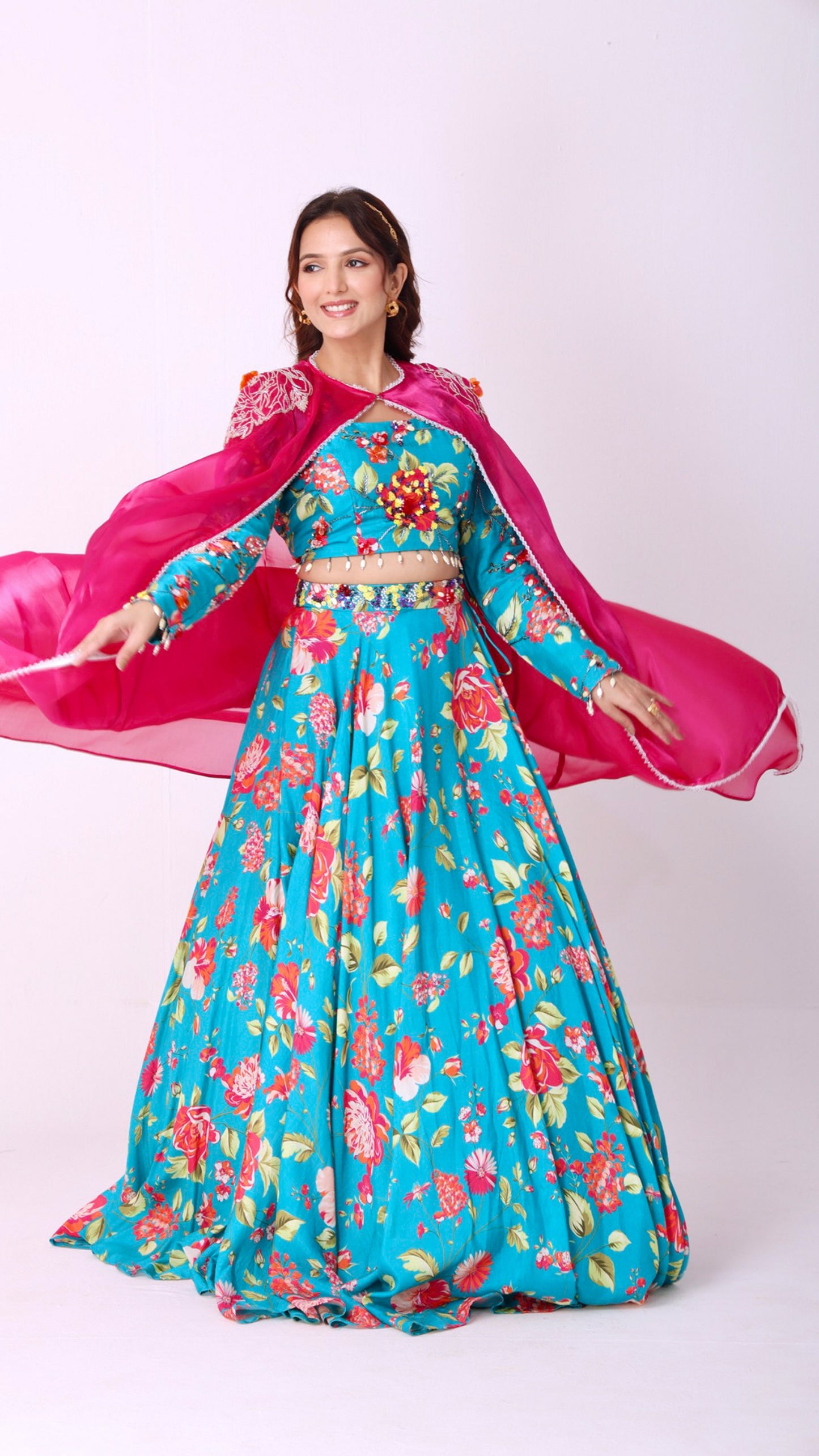 Turquoise vibrant floral lehenga choli set paired with a embroidered cape