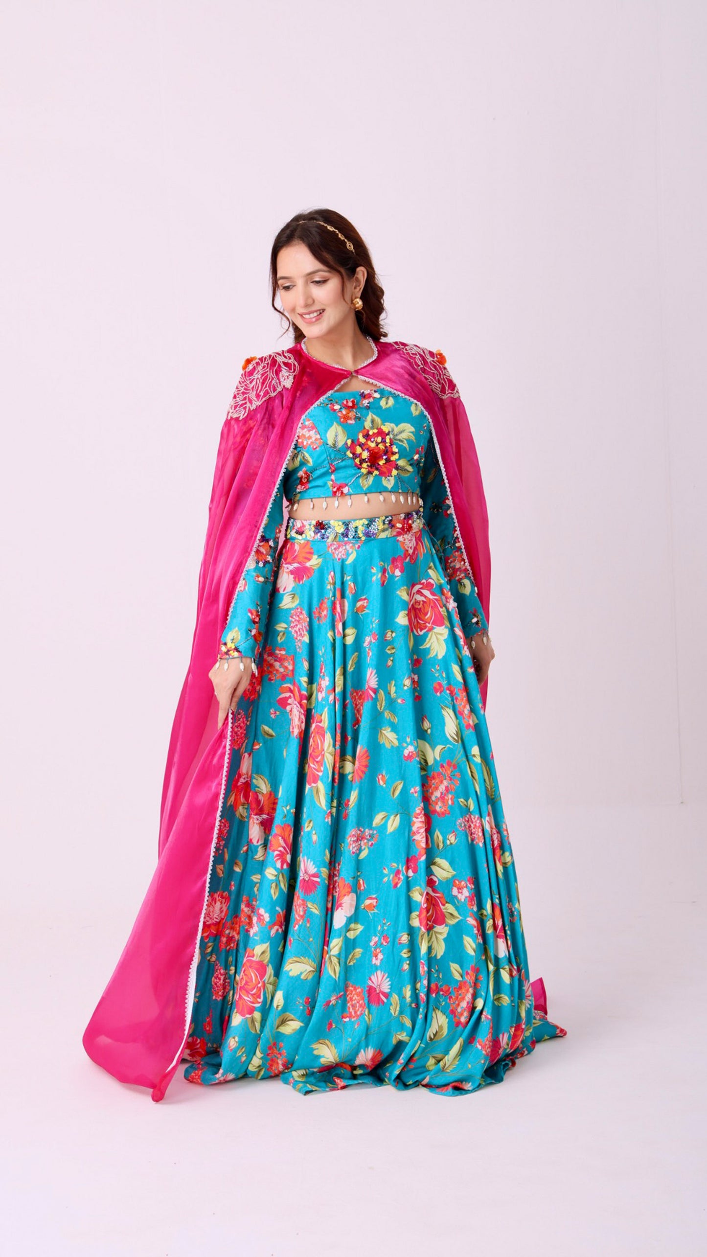 Turquoise vibrant floral lehenga choli set paired with a embroidered cape