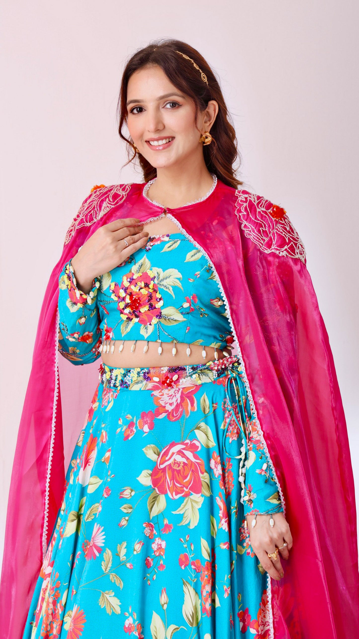 Turquoise vibrant floral lehenga choli set paired with a embroidered cape