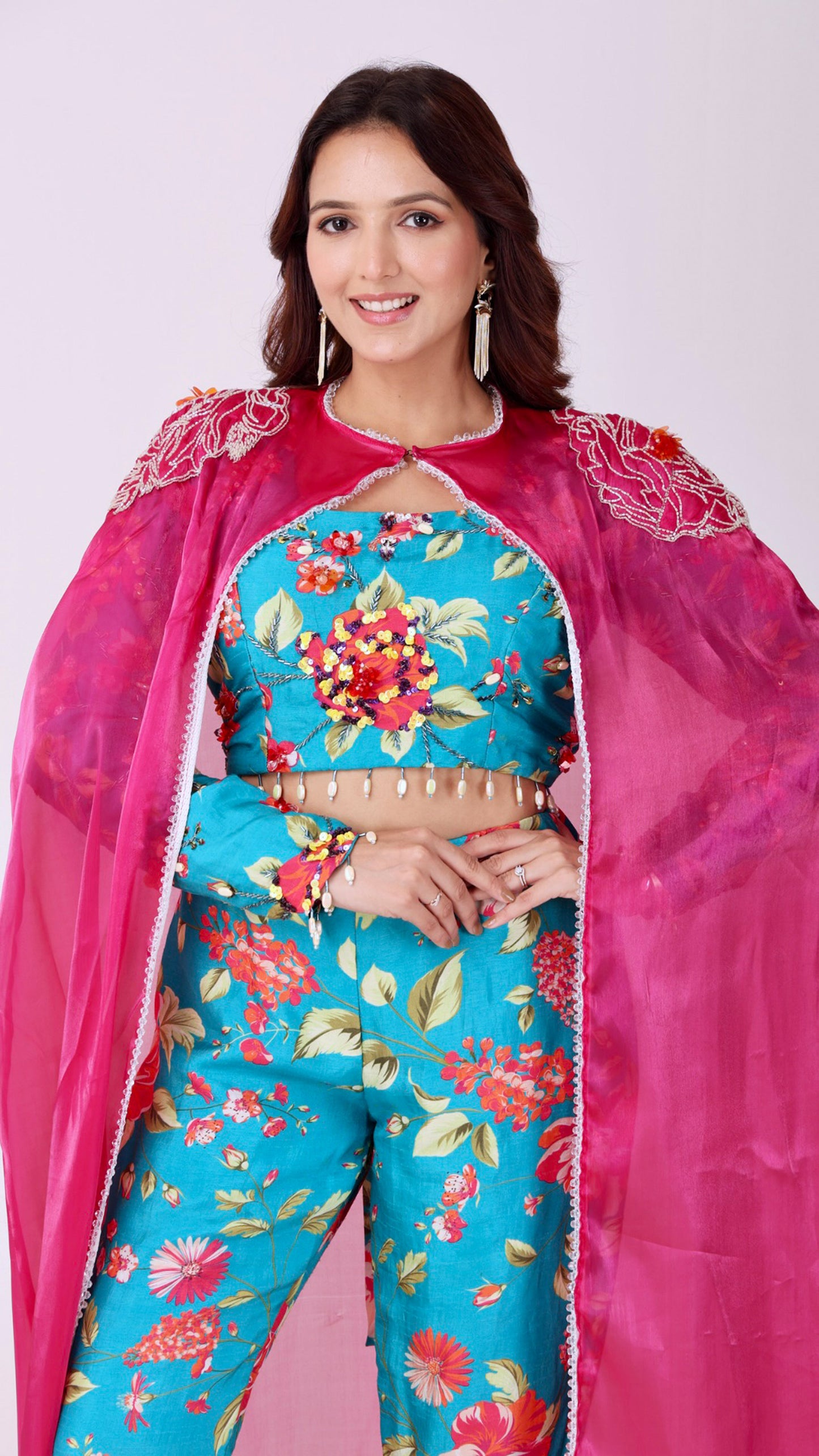 Floral embroidered turquoise co-ord set paired with a statement pink cape